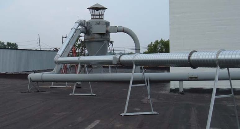 Industrial cyclone dust collection system with corrugated metal ductwork on a rooftop